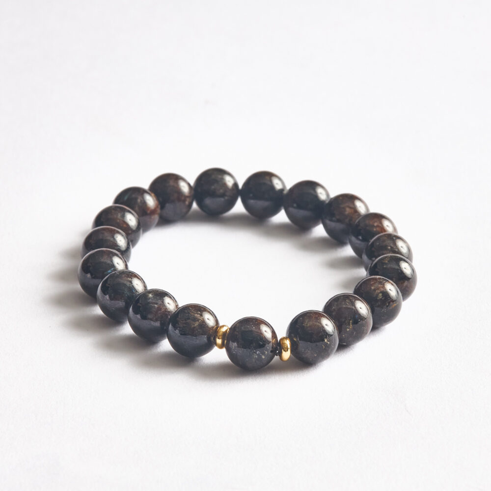 Koyu zeminli 10 mm astrophyllite boncuklarda bronz yansımalar yakın plan.