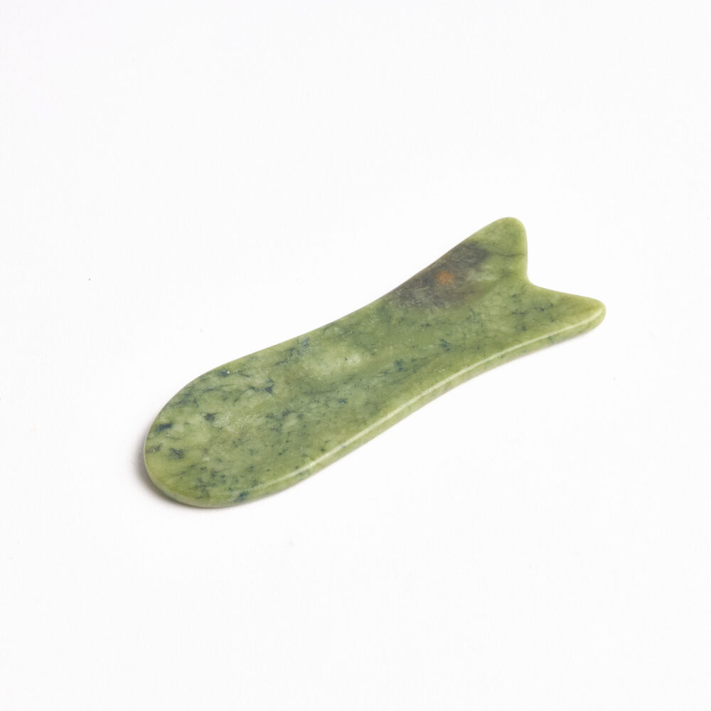 Jade gua sha yakın plan – kıvrımlı kenar detayı.